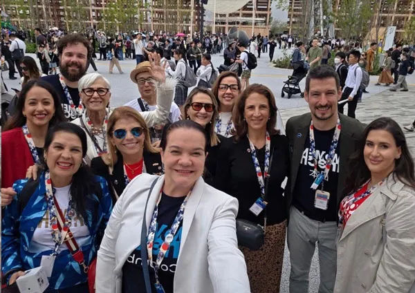 Grupo de asistentes con credenciales se toman una selfie al aire libre en Osaka durante la cumbre