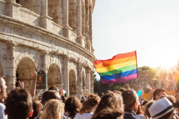 Bandera arcoíris ondeando entre una multitud frente al Coliseo de Roma