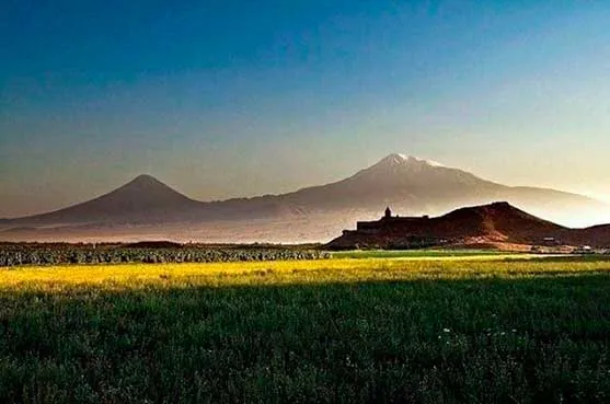 Campo verde y amarillo al atardecer con el monte Ararat al fondo, en Armenia