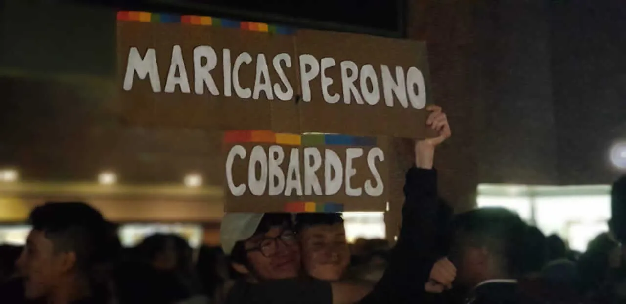 Manifestante levanta carteles con la frase «Maricas pero no cobardes» entre la multitud