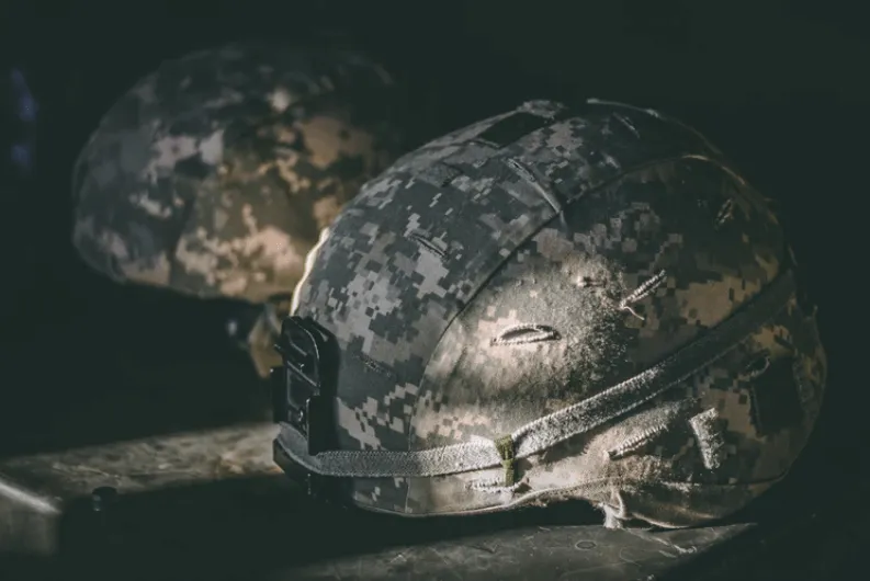 Dos cascos militares de camuflaje sobre una superficie oscura