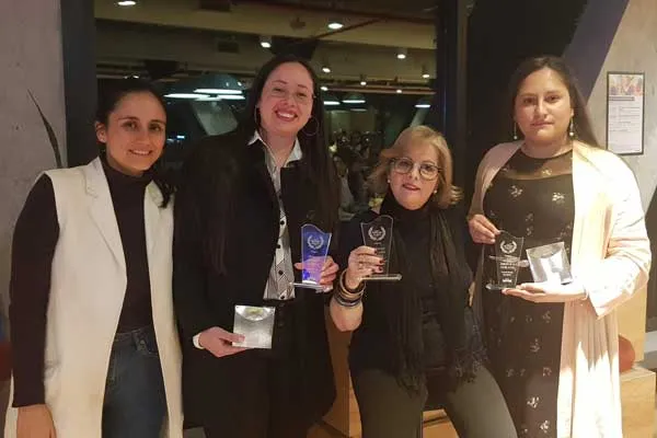 Cuatro mujeres posan sonrientes con trofeos de cristal tras una ceremonia de premiación
