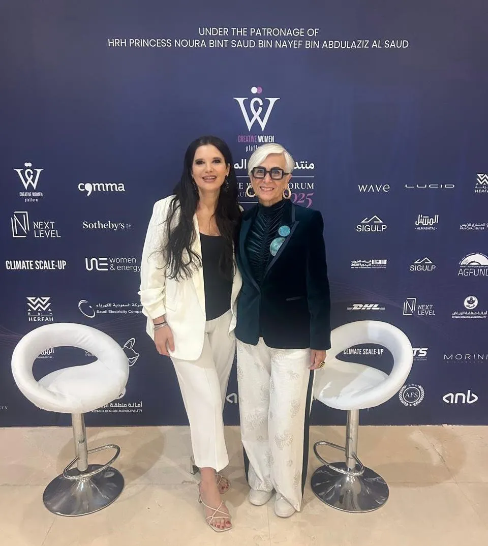 Dos mujeres posan ante el panel de patrocinadores del Creative Women Forum