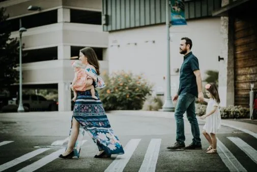 Familia cruza una calle por un paso peatonal: una mujer con un bebé, un hombre y una niña