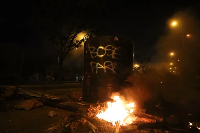 Fogata encendida en la vía junto a un muro con pintadas, en una noche de protestas
