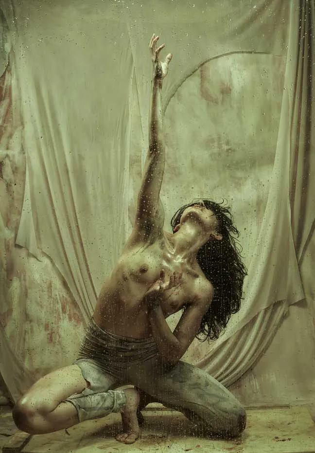Bailarina agachada con un brazo estirado hacia arriba y la cabeza hacia atrás, en una foto-performance de danza contemporánea
