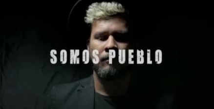 Fotograma del video «Somos Pueblo» de Autor Anónimo, con un hombre barbado y el texto «Somos Pueblo»