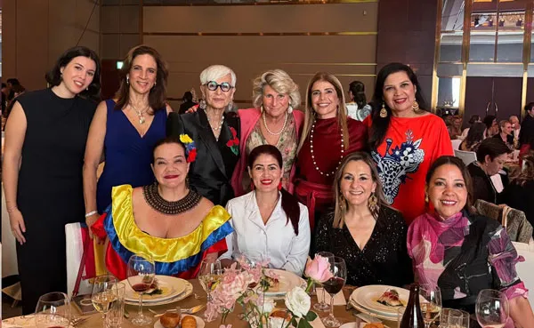 Grupo de mujeres sentadas y de pie alrededor de una mesa de banquete durante la cumbre de mujeres en tecnología
