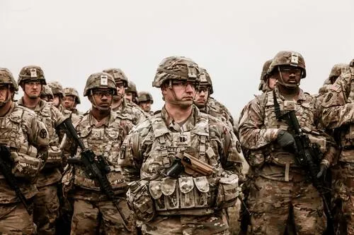 Grupo de soldados con uniforme de camuflaje, casco y fusiles posando en formación