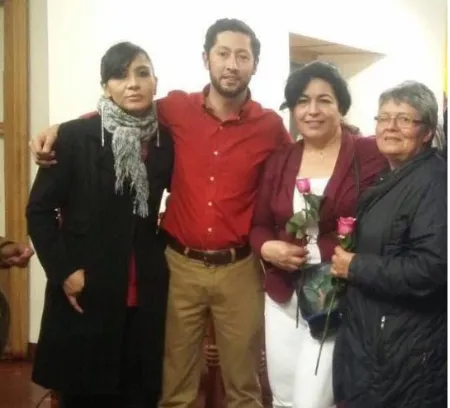 Un hombre de camisa roja y tres mujeres, dos de ellas con rosas, posan juntos en un salón