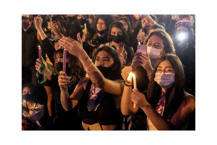 Mujeres con mascarilla levantan sus celulares y velas encendidas en la huelga del 8 de marzo de 2021
