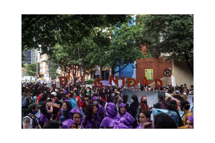 Multitud de mujeres con capuchas y prendas moradas bajo los árboles en la huelga del 8 de marzo de 2021