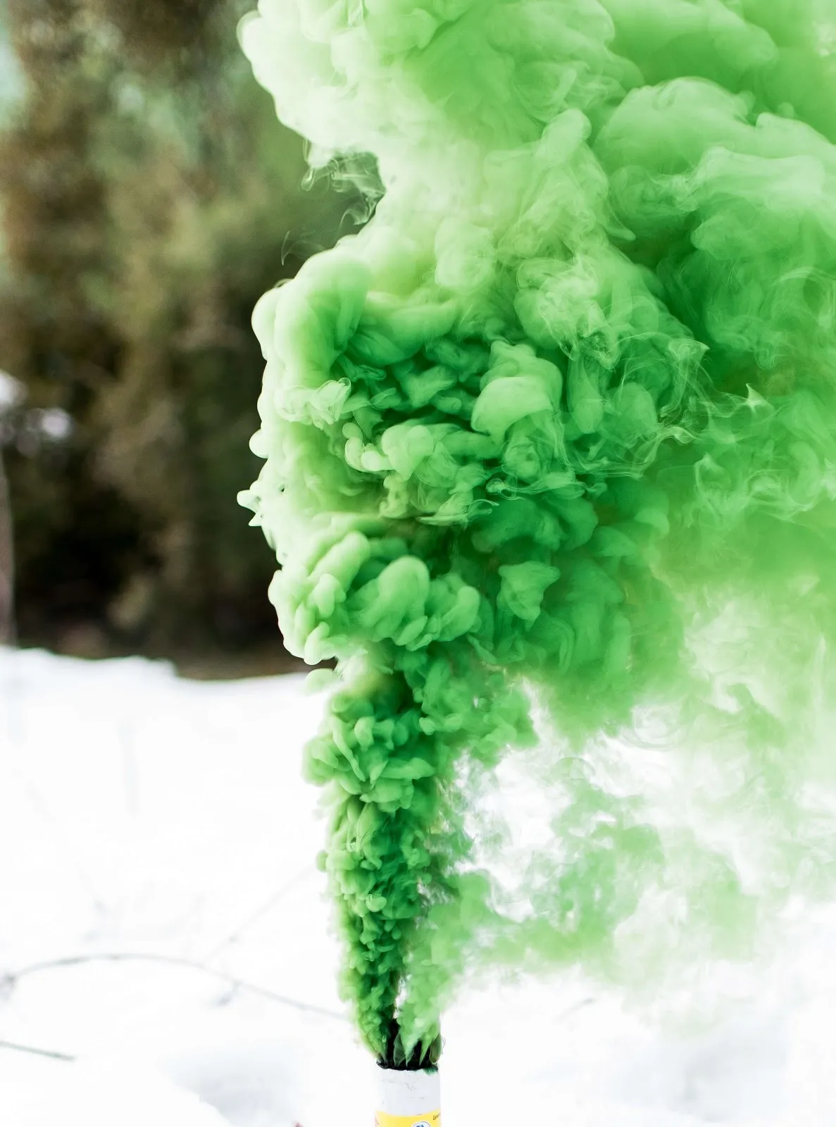 Humo verde de una bengala entre árboles y nieve, color de la marea verde por el aborto legal