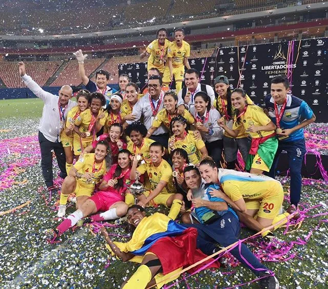 Jugadoras y cuerpo técnico con uniforme amarillo celebran entre confeti en el estadio, tras una final de la Copa Libertadores Femenina