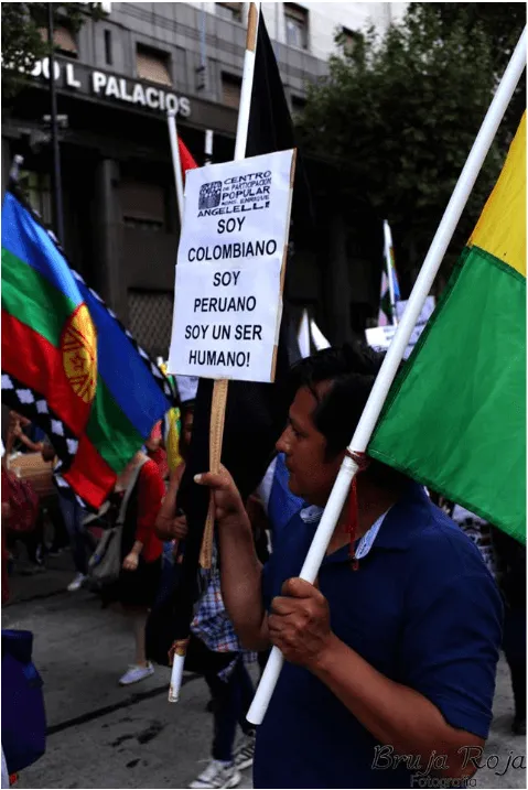 Manifestante con banderas y un cartel «Soy colombiano, soy peruano, soy un ser humano» en una marcha migrante