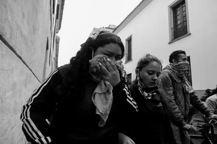 Manifestantes se cubren el rostro con pañuelos durante una protesta, en blanco y negro
