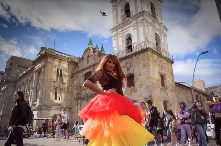 Persona con una falda de tul rojo y naranja baila frente a una iglesia histórica durante la Marcha del Orgullo