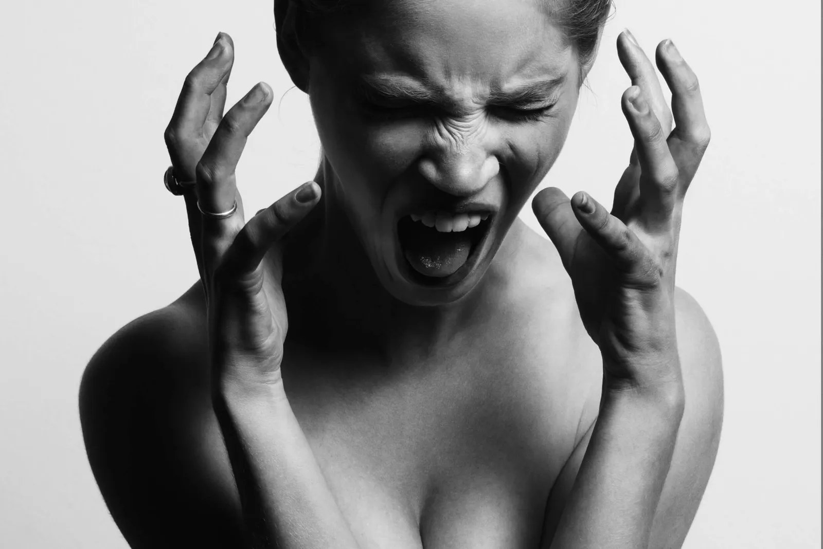 Mujer en blanco y negro con gesto de gritar y las manos junto a la cabeza