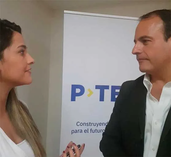 Mujer y hombre conversan de perfil frente a un cartel de P-TECH
