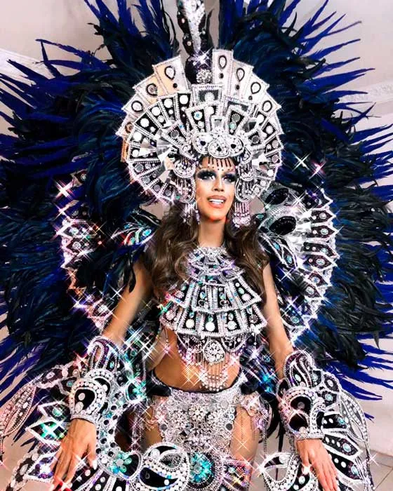 Mujer con un traje de carnaval de plumas azules oscuras y lentejuelas plateadas, con gran penacho