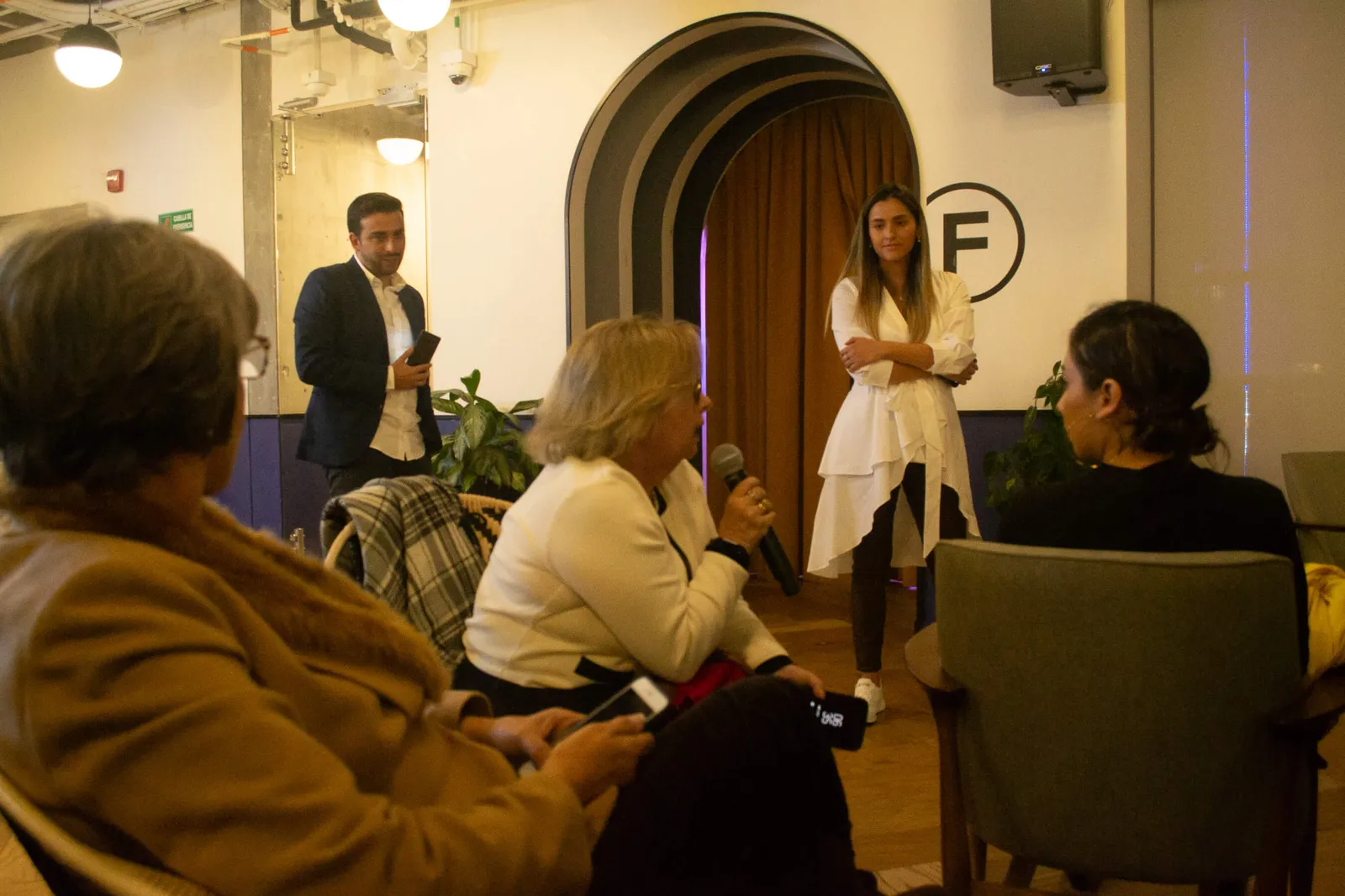 Mujeres sentadas conversan con una oradora de pie con micrófono en el lanzamiento de Revista Level