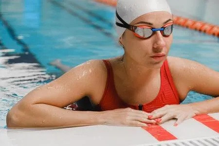 Nadadora con gorro blanco y gafas apoyada en el borde de una piscina