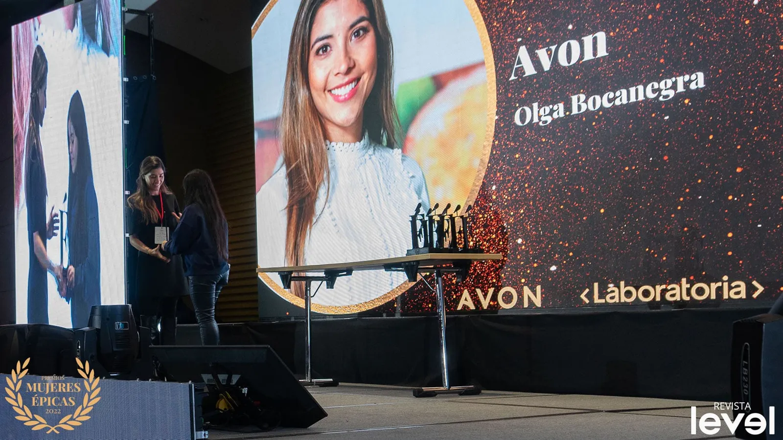 Pantalla del escenario de los Premios Mujeres Épicas de Revista Level con la foto y el nombre de Olga Bocanegra, de Avon