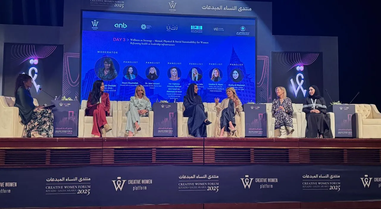 Panel de discusión de mujeres sentadas en un escenario con una pantalla azul y el logo del Creative Women Forum 2025