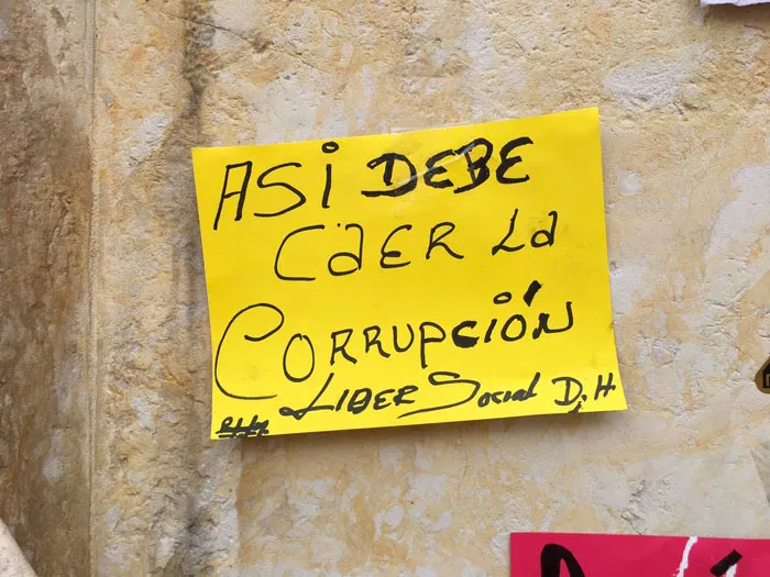 Papel amarillo pegado en un muro con el mensaje «Así debe caer la corrupción»