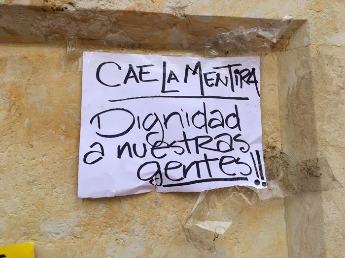 Papel pegado en un muro con el mensaje «Cae la mentira, dignidad a nuestras gentes!!»