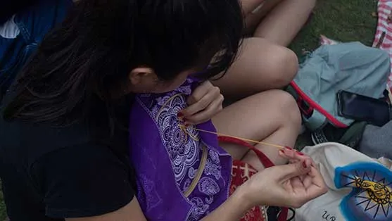 Persona bordando una tela morada sentada en el pasto durante el 8M en Bucaramanga