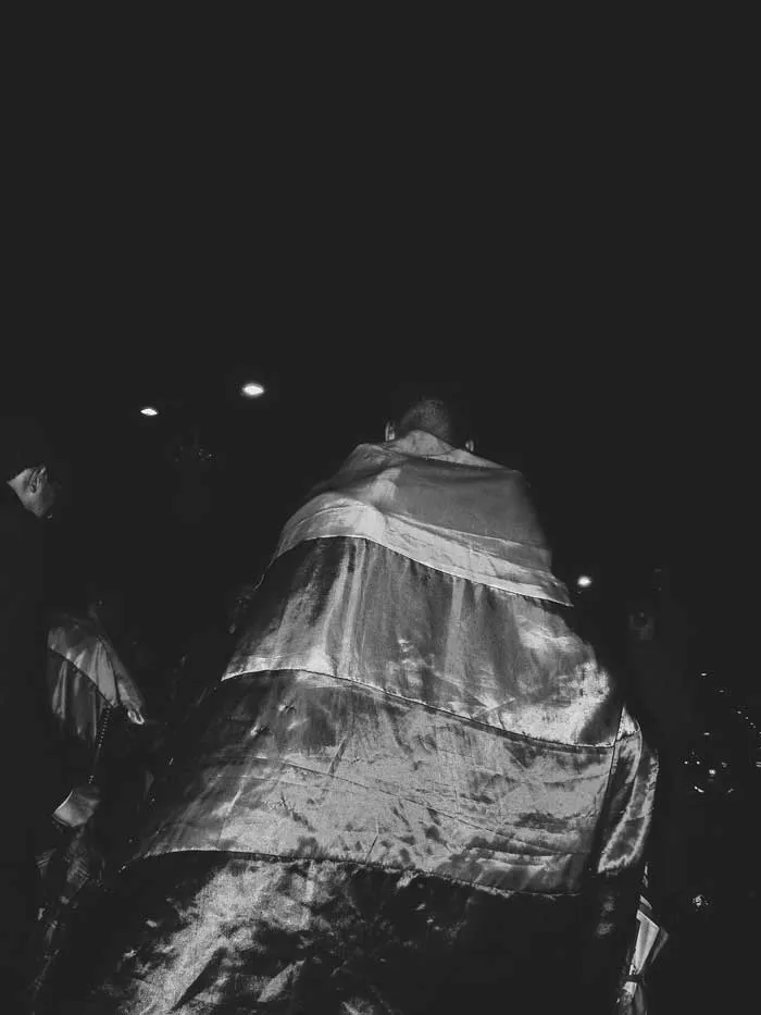 Persona de espaldas envuelta en una bandera brillante en la oscuridad, en blanco y negro
