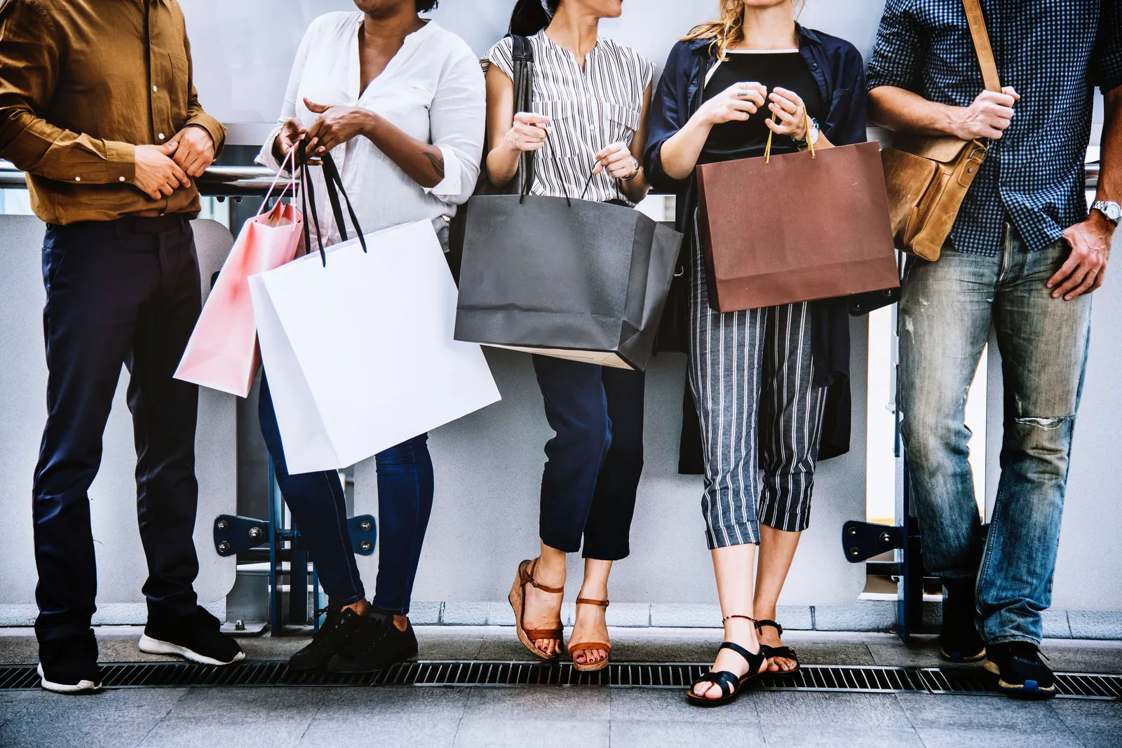 Grupo de personas de pie en fila con bolsas de compras en las manos