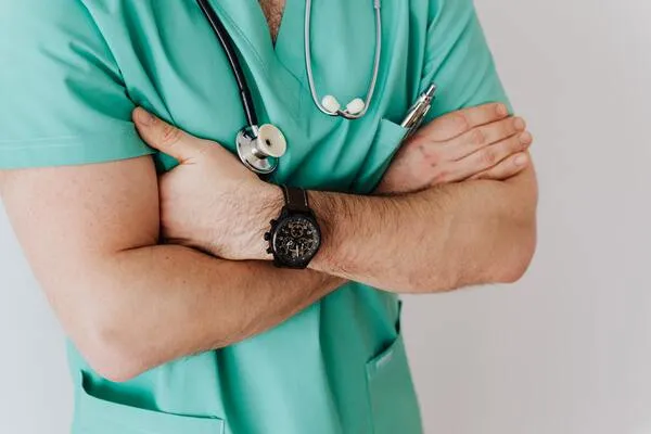 Profesional de la salud con uniforme verde y estetoscopio, con los brazos cruzados