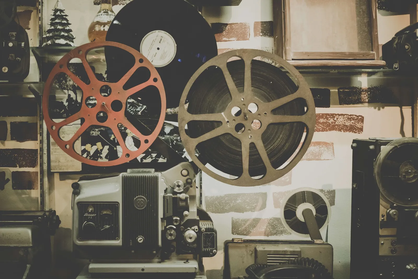 Proyector de cine antiguo con carretes de película y discos de vinilo al fondo