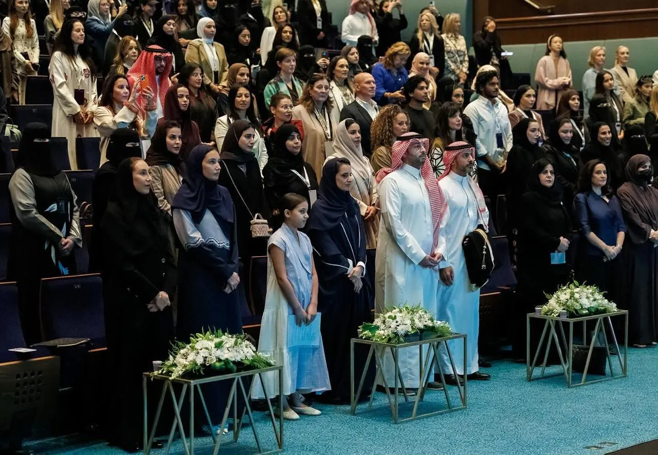 Público de pie en el auditorio del Creative Women Forum, con arreglos de flores sobre mesas