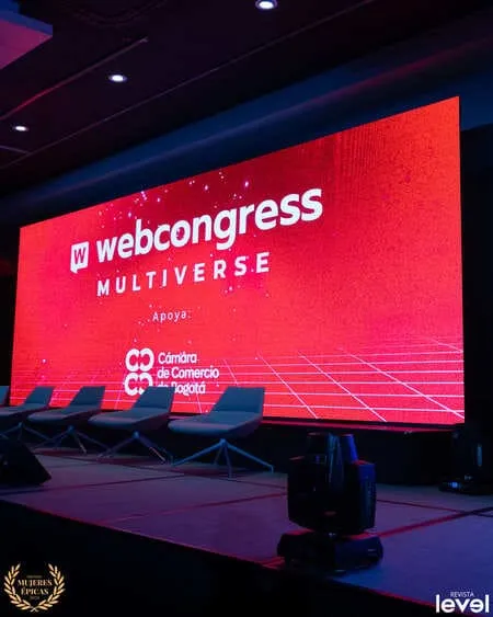 Escenario del «WebCongress Multiverse» con pantalla roja y sillas de panel, foto de Revista Level