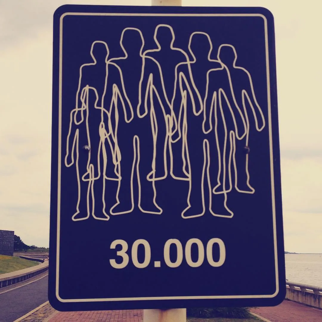 Señal azul de tránsito con siluetas de personas y la cifra «30.000» en memoria de los desaparecidos en Argentina