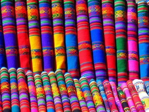 Telas de rayas de colores vivos apiladas en un puesto de artesanías