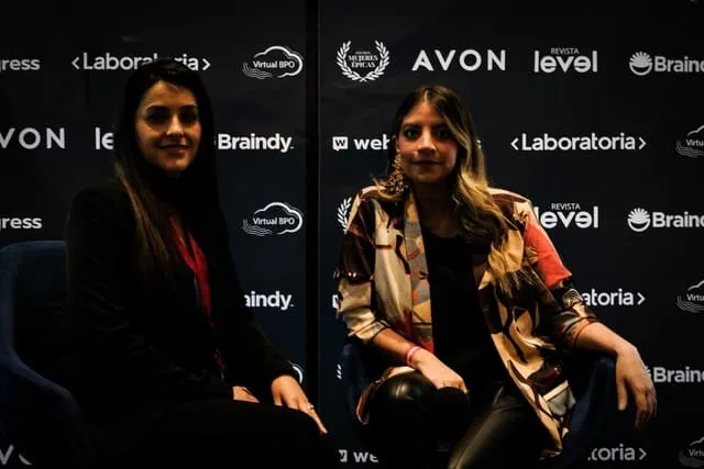 Dos mujeres sentadas en una entrevista frente a un panel con logos de patrocinadores como Avon, Laboratoria y Revista Level