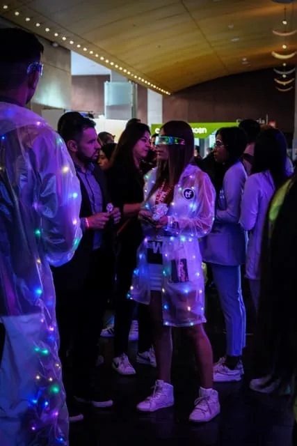 Asistente con un atuendo cubierto de luces conversa con otras personas en el WebCongress Multiverse