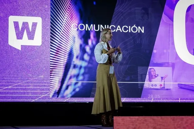 Conferencista de pie en el escenario ante una pantalla con la palabra «Comunicación» y el logo de WebCongress