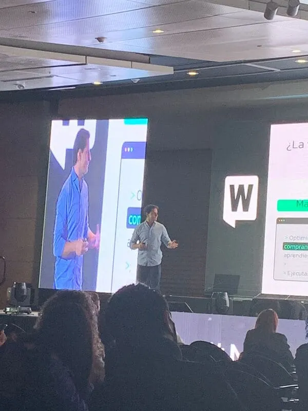 Orador presenta en el escenario del WebCongress ante una pantalla con su imagen y el logo del evento