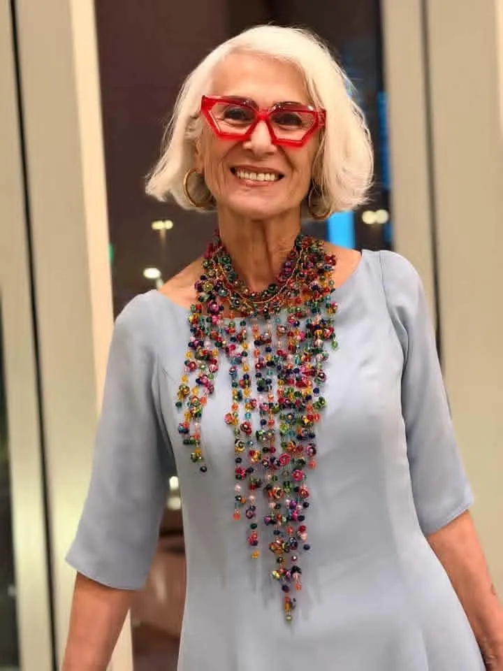 Retrato de Viola Edward con blusa gris y gafas rojas.